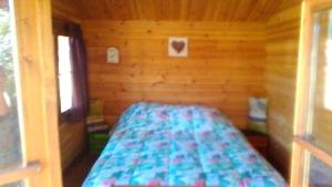 ein kleines Schlafzimmer mit einem Bett in einem Blockhaus in der Unterkunft RANCH DU PUITS DE RIQUIER in Moissac-Bellevue