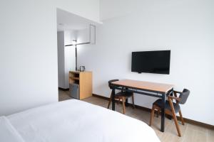 um quarto com uma cama e uma secretária com uma televisão em LIANN Hotel em Taichung