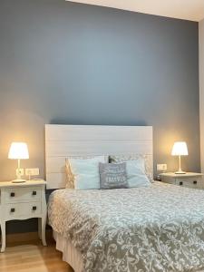a bedroom with a bed and two night stands with lamps at Apartamento Civitas in Écija