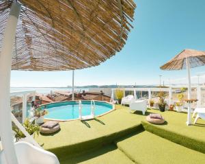 a pool on the roof of a hotel with chairs and an umbrella at Sunset Destination Hostel in Lisbon