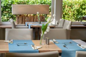 a table with blue napkins and utensils on at Das Frühstückshotel Büsum in Büsum