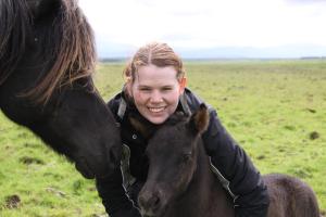 Eine junge Frau umarmt ein braunes Pferd in der Unterkunft Cabin 3 at Lundar Farm in Borgarnes