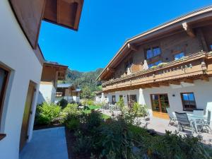 une maison avec une terrasse et des chaises dans une cour dans l'établissement Hochalmbahnen Chalets Rauris 1-06 WE2 Maislaufeldweg 1g EG, à Rauris
