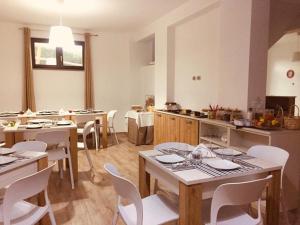 B&B Le Cinque Cime في فيدجانيلو: مطبخ كبير مع طاولات وكراسي بيضاء في الغرفة