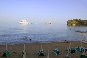 a cruise ship in the water with chairs on the beach at Hotel Lido Mediterranee in Taormina
