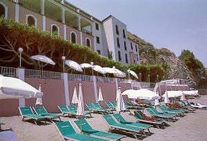 a bunch of lounge chairs and umbrellas on a beach at Hotel Lido Mediterranee in Taormina