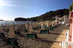 a row of beach chairs and umbrellas on a beach at Hotel Lido Mediterranee in Taormina