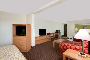 a hotel room with a bed and a couch and a television at Days Inn by Wyndham Fort Dodge in Fort Dodge