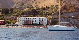 una barca a vela bianca in acqua vicino a una spiaggia di Hotel Lido Mediterranee a Taormina