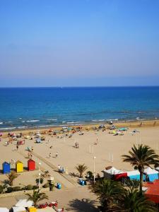 a beach with a lot of people and the ocean at 1ere soleil levant in Puerto de Sagunto