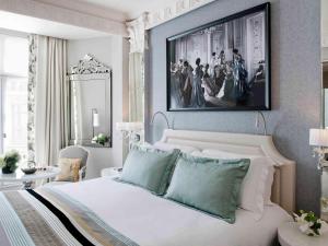 a bedroom with a white bed and a painting on the wall at Sofitel Paris Le Faubourg in Paris
