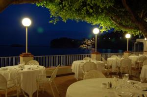 a restaurant with white tables and chairs at night at Hotel Lido Mediterranee in Taormina