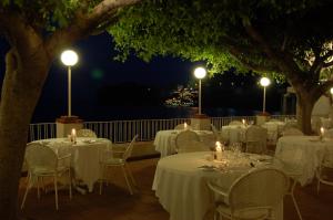 a row of tables and chairs on a deck at night at Hotel Lido Mediterranee in Taormina