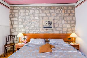 a bedroom with a bed and a stone wall at Apartments Nicol in Dubrovnik