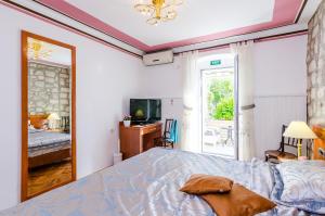 a bedroom with a bed and a tv and a window at Apartments Nicol in Dubrovnik
