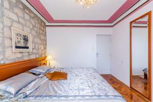 a bedroom with a bed and a stone wall at Apartments Nicol in Dubrovnik