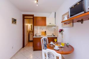 a small kitchen with a wooden table and a table and chairs at Apartments Nicol in Dubrovnik