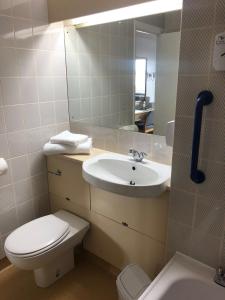 een badkamer met een wastafel, een toilet en een spiegel bij Redwings Lodge Rutland in Uppingham