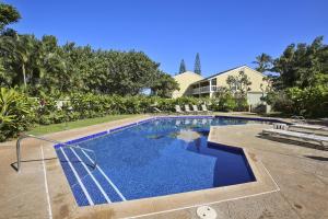 a swimming pool with blue water in front of a house at Turtle Bay Sea BreezeNUC 90-TVU-0498 in Kahuku