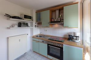 cocina con armarios verdes, fregadero y fogones en Ferienwohnung Mohnblume - Strandhaus Lobbe, en Middelhagen