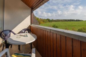 una mesa y sillas en un balcón con vistas a un campo en Ferienwohnung Mohnblume - Strandhaus Lobbe, en Middelhagen