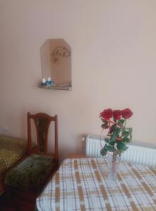 a room with a table with a vase with roses on it at Park House in Pochayiv