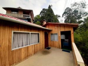 ein Holzhaus mit einer Garage und einem Gebäude in der Unterkunft Joe's Farm in Darjeeling