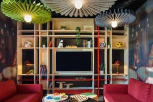 sala de estar con TV y 2 sillas rojas en ibis Clamart Paris Velizy, en Clamart