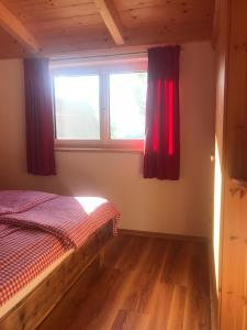 1 dormitorio con 1 cama y una ventana con cortinas rojas en Apartment Wohlesser, en Neumarkt in Steiermark