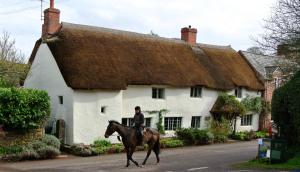 a person riding a horse in front of a house at Notley Arms Inn Exmoor National Park in Elworthy