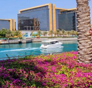 un barco en un río frente a un edificio en شقق نسيم البحر, en King Abdullah Economic City