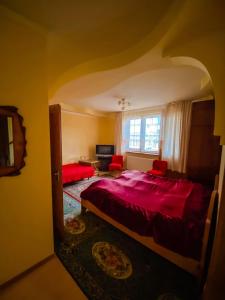 Un dormitorio con una gran cama roja y una ventana en Domashnya Saduba, en Mukácheve