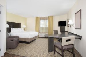 Candlewood Suites Longmont - Boulder Area, an IHG Hotel في لونغمونت: فندق غرفه بسرير ومكتب وسرير