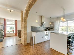 una cucina a pianta aperta con armadietti bianchi e un muro di mattoni di Classy Holiday Home in Langezwaag with Terrace a Langezwaag