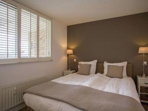 1 dormitorio con 1 cama grande con sábanas y almohadas blancas en Apartment at the promenade and beach, en Noordwijk