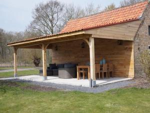 een groot houten paviljoen met een tafel en een bank bij from the Zealand coast and 20km from Brugge in Aardenburg