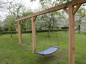 un columpio en un parque con árboles en Cosy holiday home with pet friendly garden en Elsendorp