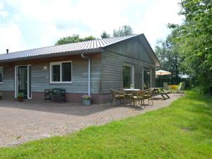 una casa con patio arredato con tavolo e sedie di Holiday home with view over the meadows a Kibbelveen