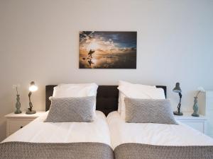 a bedroom with two beds and a painting on the wall at Apartment overlooking the Scheveningen harbor in Scheveningen