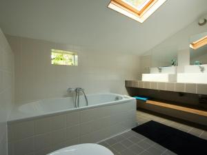 a bathroom with a tub and a toilet and a sink at Spacious Farmhouse near Forest in Stramproy in De Horst