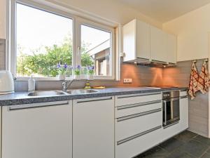 una cocina con armarios blancos y una ventana en Luxury Holiday Home with Terrace, en Beek