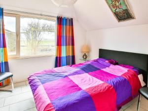 um quarto com uma cama colorida e uma janela em Quaint Holiday Home with sauna and Jacuzzi em Gerkesklooster