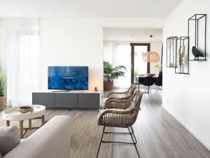 a living room with two chairs and a tv at Sea view apartment in Den Haag with terrace in Scheveningen