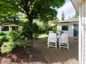 un patio con mesa y sillas bajo un árbol en Tasteful chalet near Ommen for family, en Stegeren