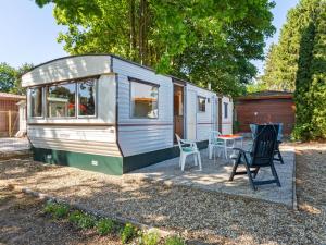 una pequeña caravana con una mesa y sillas en un patio en Comfortable holiday home in Garderen en Garderen