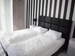 ein weißes Bett mit einem schwarzen Kopfteil und weißen Kissen in der Unterkunft Holiday Home in Zeewolde with Jetty next to golf course in Zeewolde