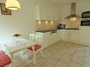 a kitchen with white cabinets and a table and chairs at Restored farmhouse in Wijlre with two terraces in Wijlre