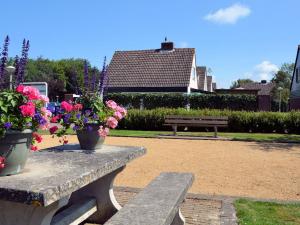een parkbankje met twee vazen bloemen erop bij Lovely Holiday Home in Noordwijkerhout near Lake in Noordwijkerhout