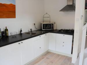 een keuken met witte kasten en een magnetron bij Lovely Holiday Home in Noordwijkerhout near Lake in Noordwijkerhout