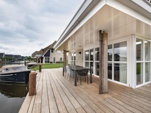 una terraza de madera con una mesa y un barco sobre el agua en Luxury villa with a sauna, at the Tjeukemeer, en Delfstrahuizen